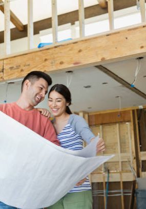 Smiling young couple checking blueprints at home
